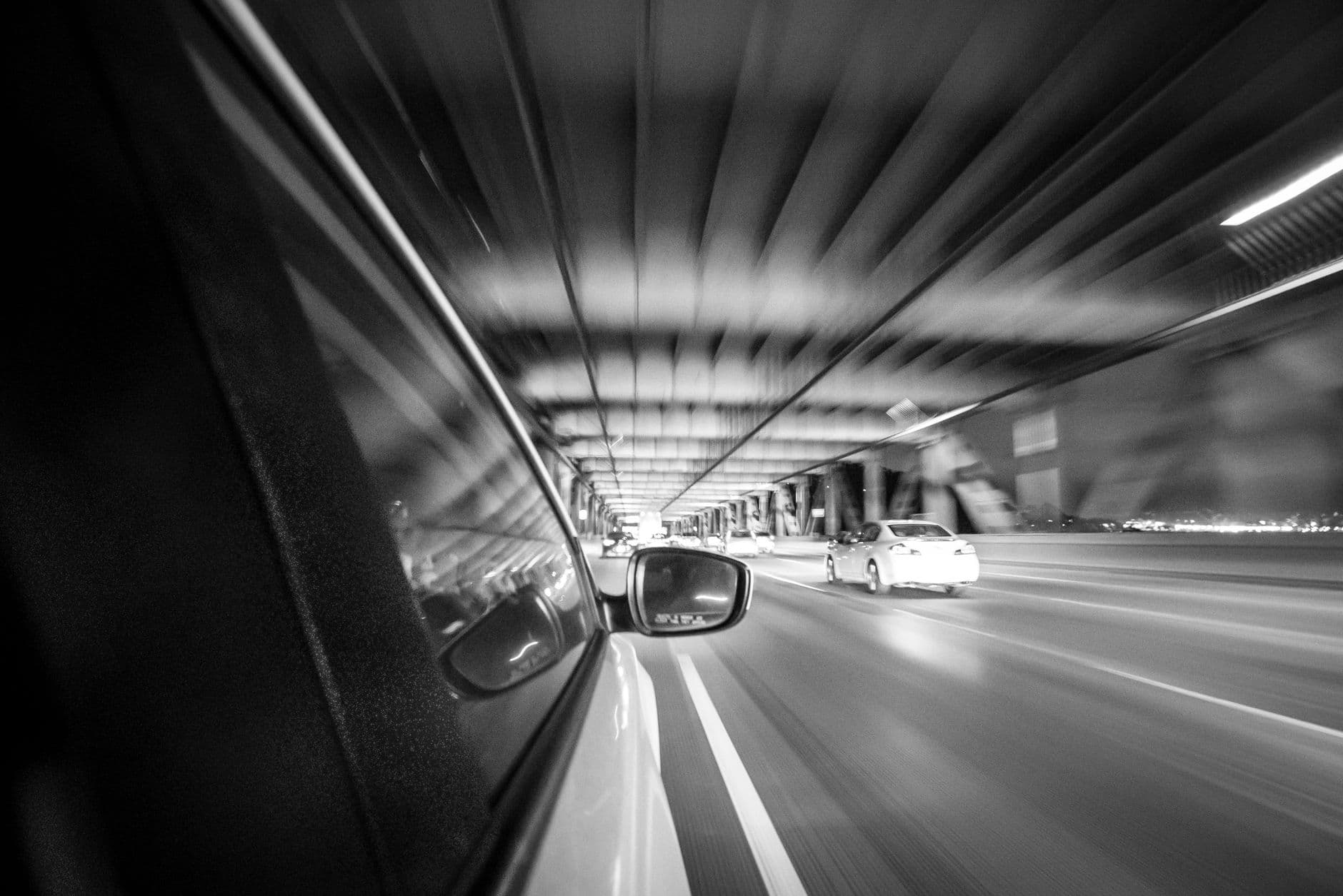 Black and white motion blur shot from a car on a San Francisco bridge at night.