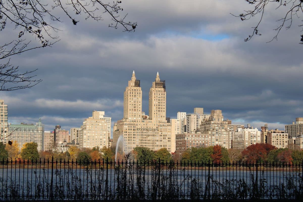 View of New York City's skyline from Central Park with autumn trees and water.