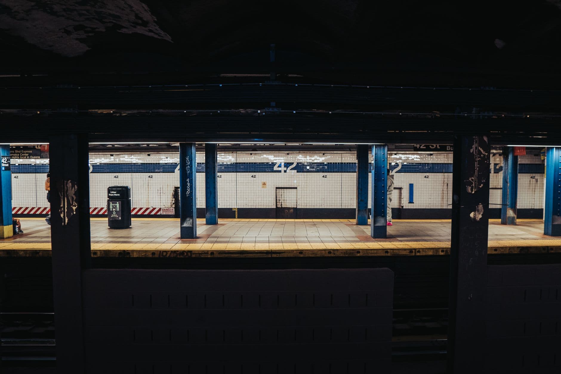 Empty subway platform with blue pillars at 42nd Street Station in New York City.